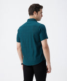 Man wearing a green pure cotton textured shirt green with casual styling on a gray background