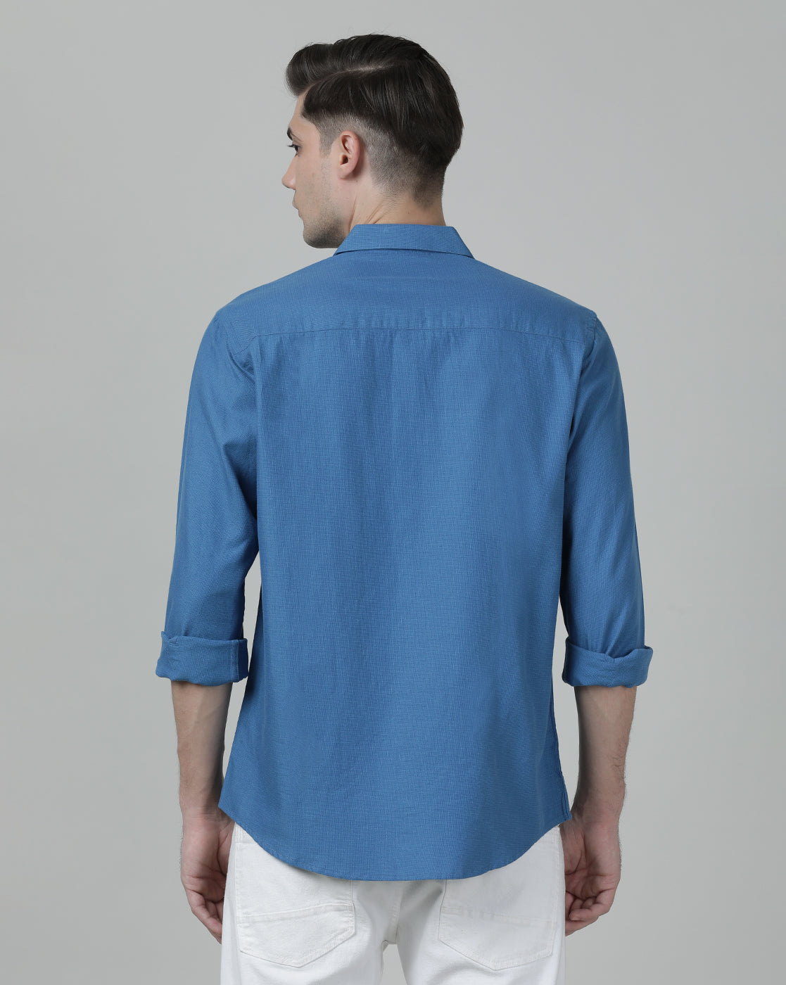 Man wearing a blue royal blue solid full sleeve linen shirt on a light gray background