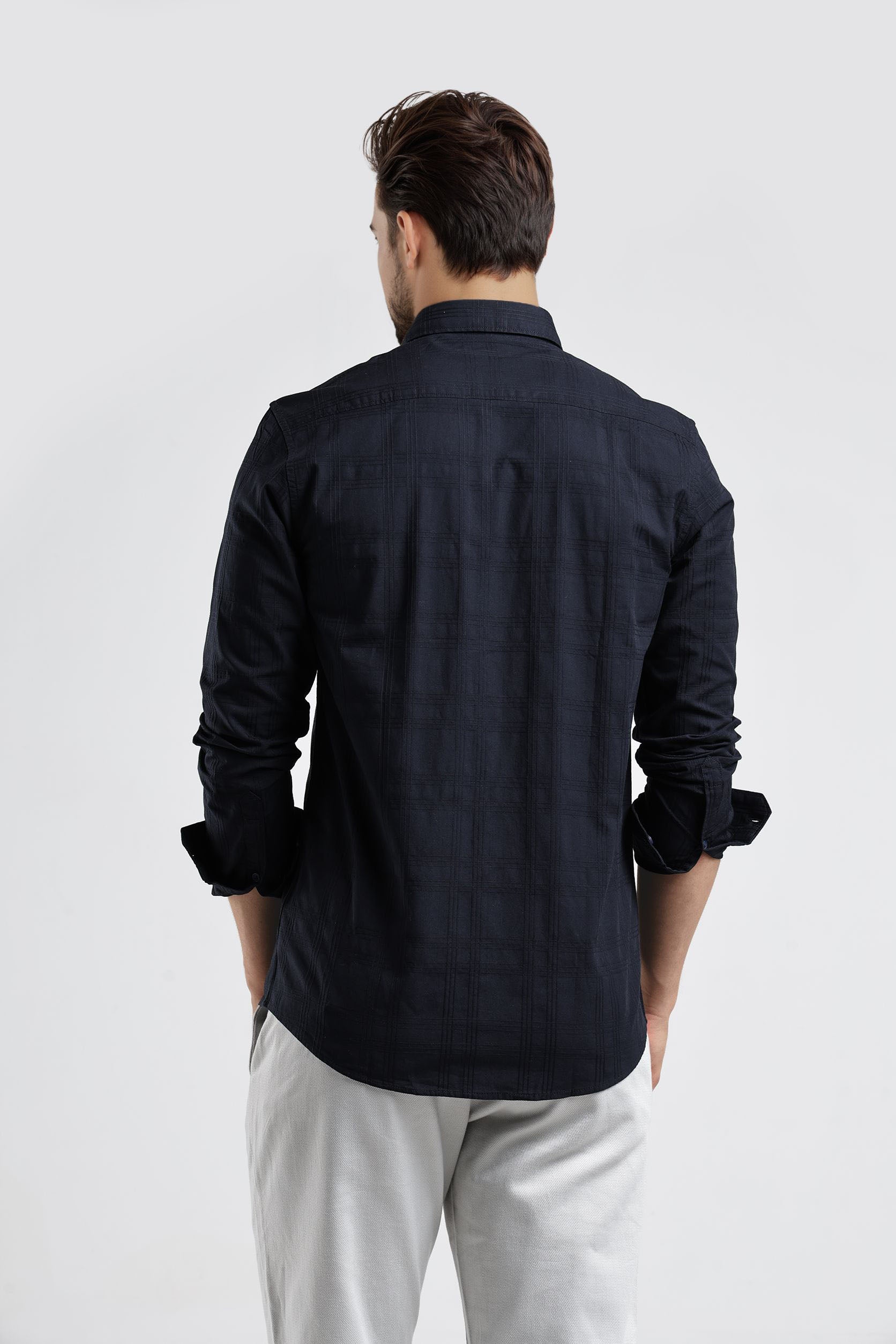 Man wearing a black shirt and light gray pants on a white background