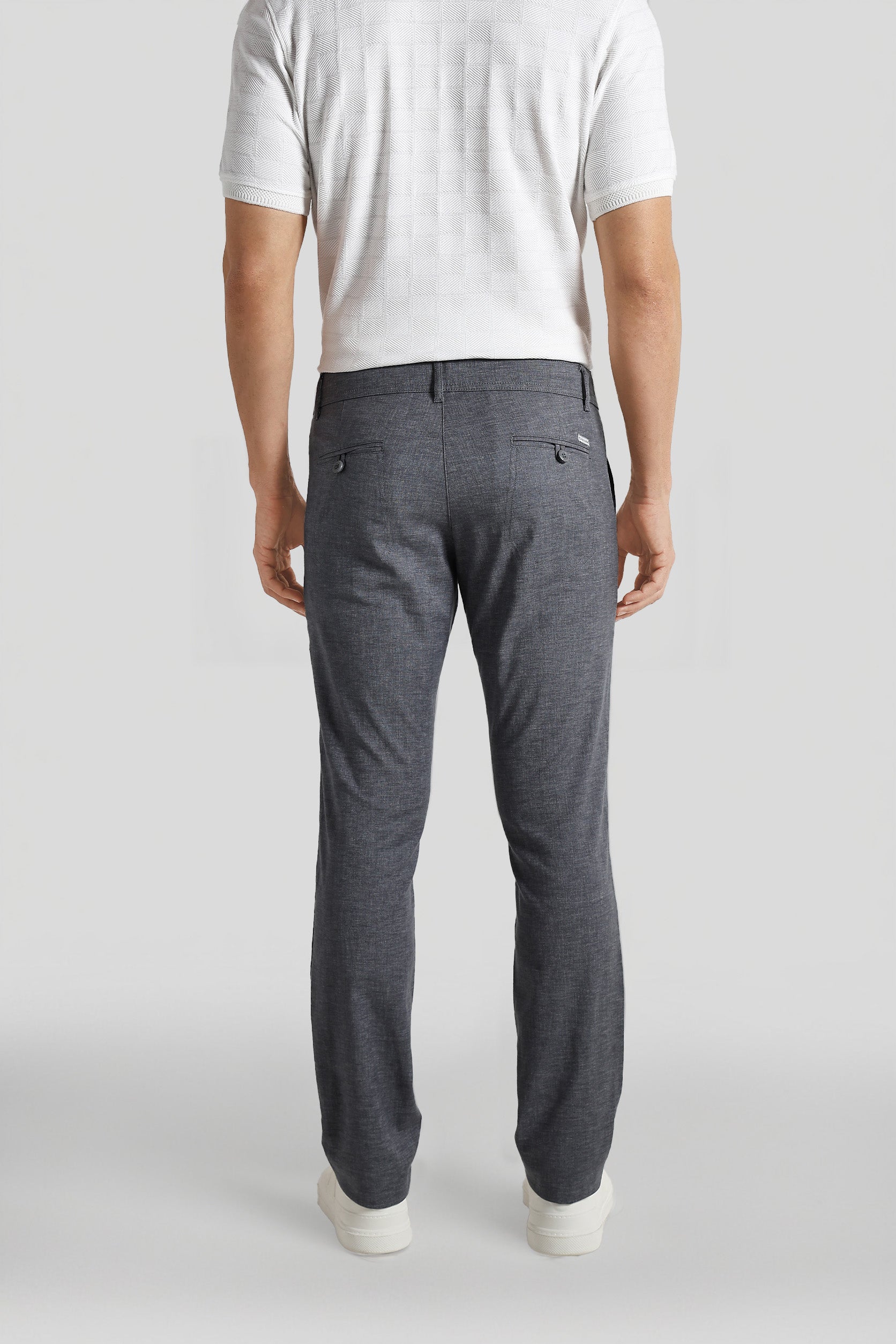 Person wearing gray pants and a white shirt on a plain background