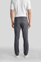 Person wearing gray pants and a white shirt on a plain background