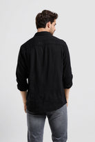 Man wearing a black shirt and gray pants on a white background