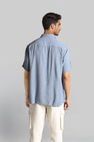 Man wearing a light blue shirt and beige pants against a gray background