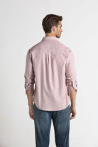 Man wearing a light pink shirt and blue jeans on a white background