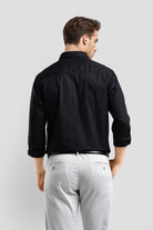 Man wearing a black shirt and gray pants on a light gray background