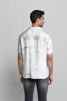 Man wearing a white short-sleeve shirt and dark jeans on a light gray background