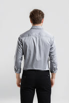 Man wearing a light blue denim shirt and black pants on a white background