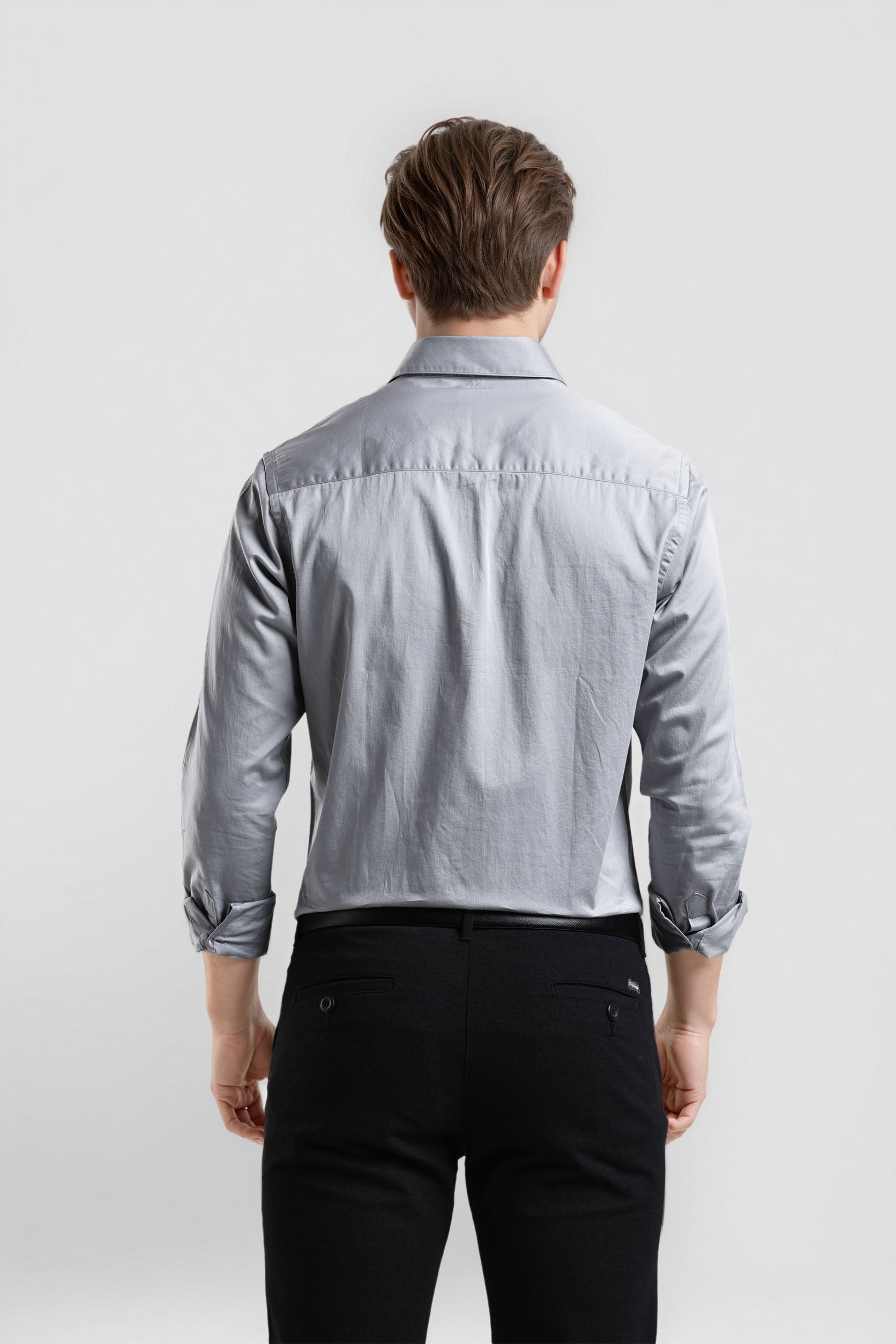 Man wearing a light blue denim shirt and black pants on a white background