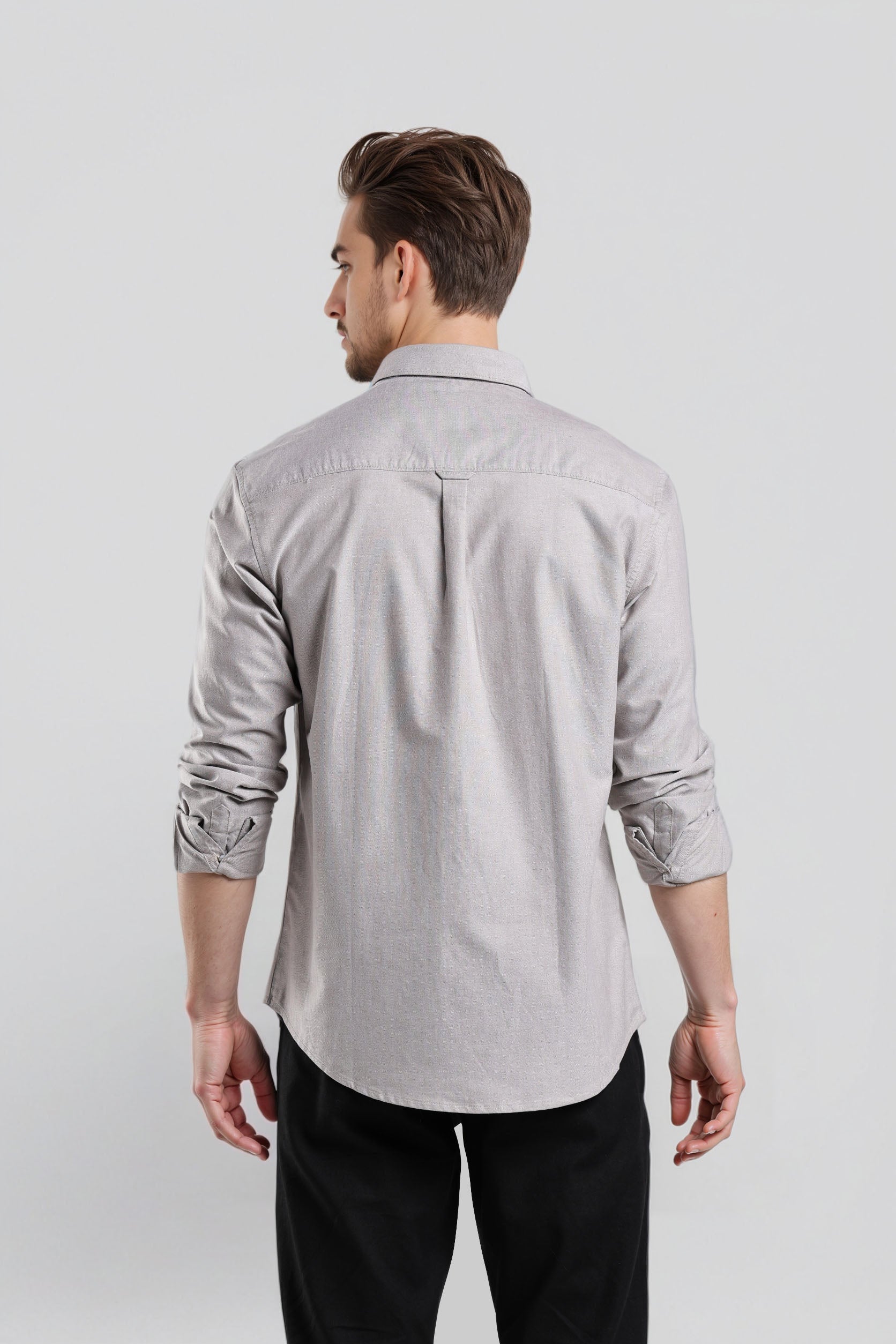 Man wearing a light gray button-up shirt and black pants on a white background