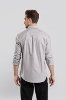 Man wearing a light gray button-up shirt and black pants on a white background