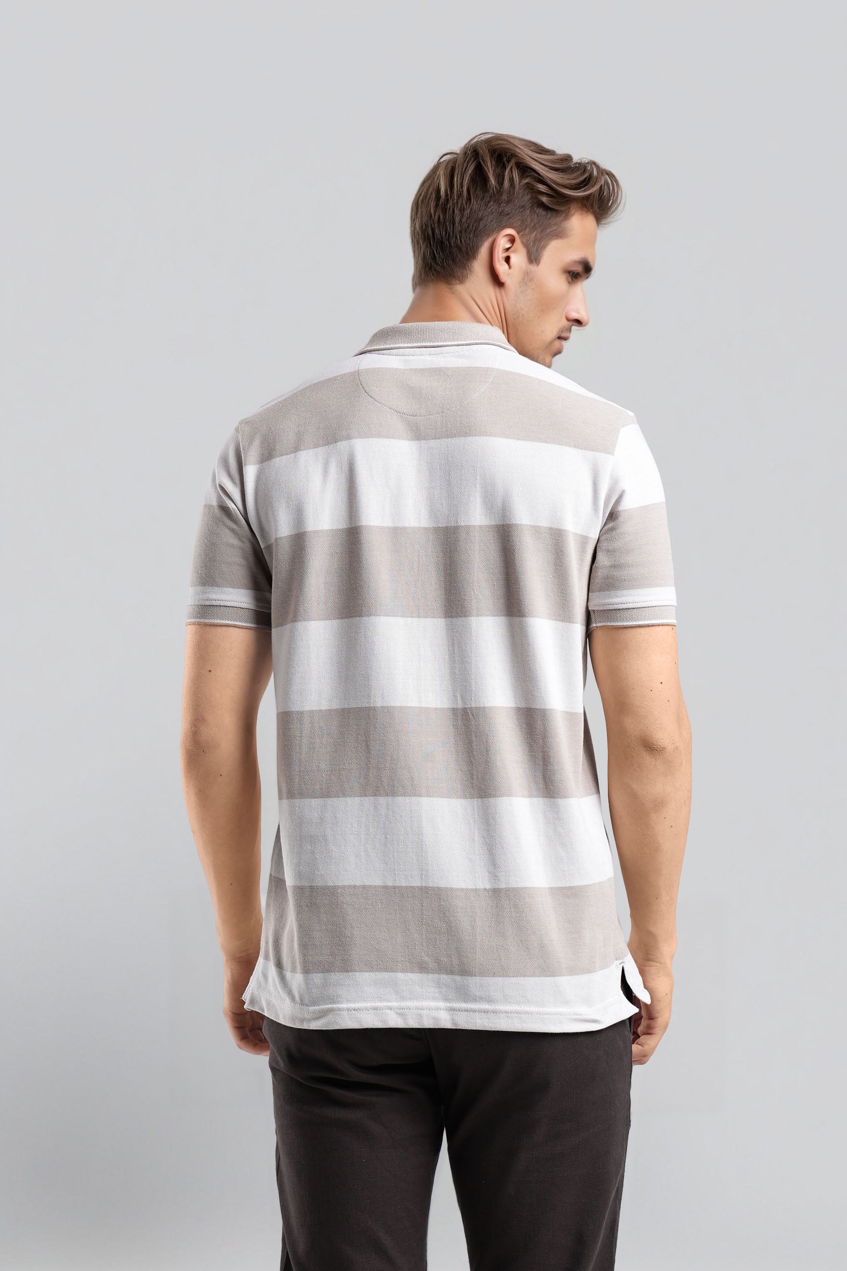 Man wearing a gray and white striped polo shirt on a light gray background