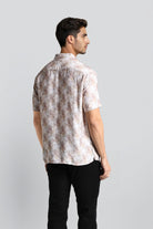 Man wearing a patterned shirt and black pants on a light gray background