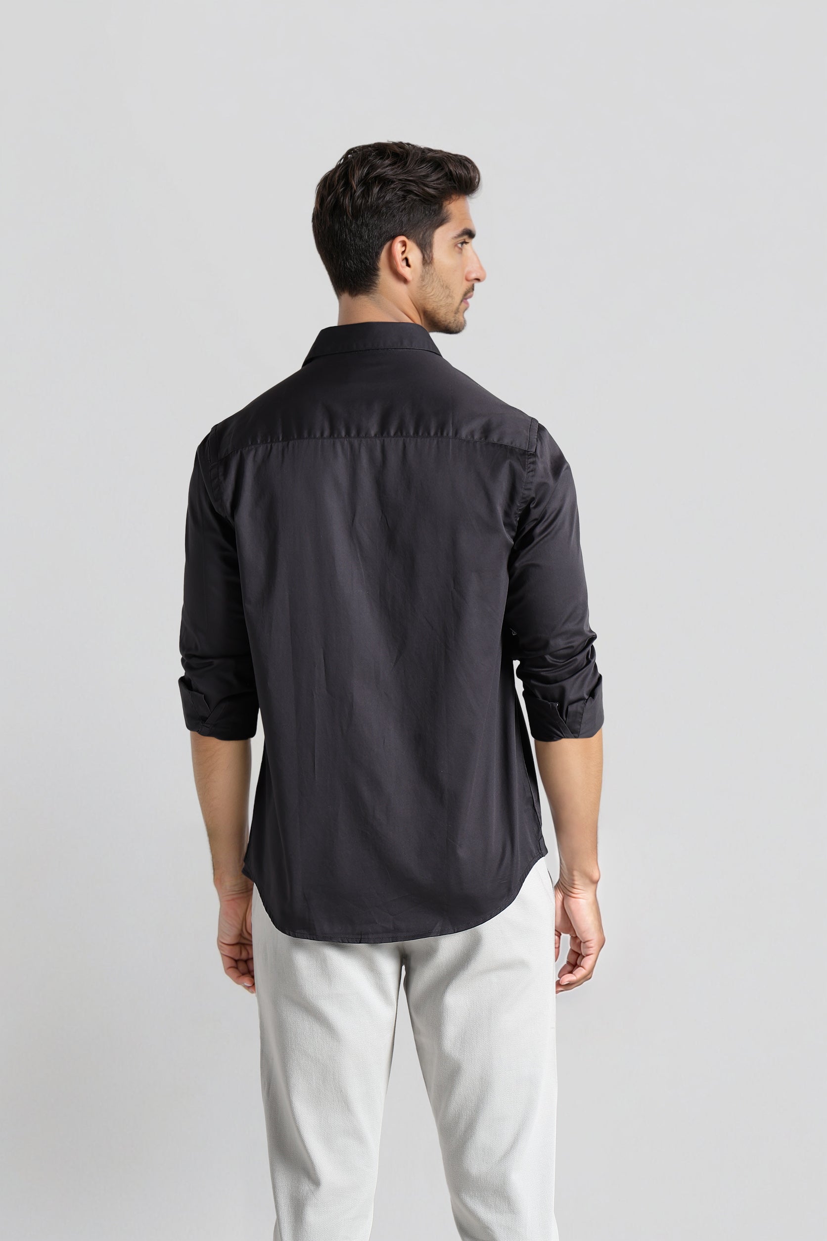 Man wearing a black shirt and light gray pants on a white background