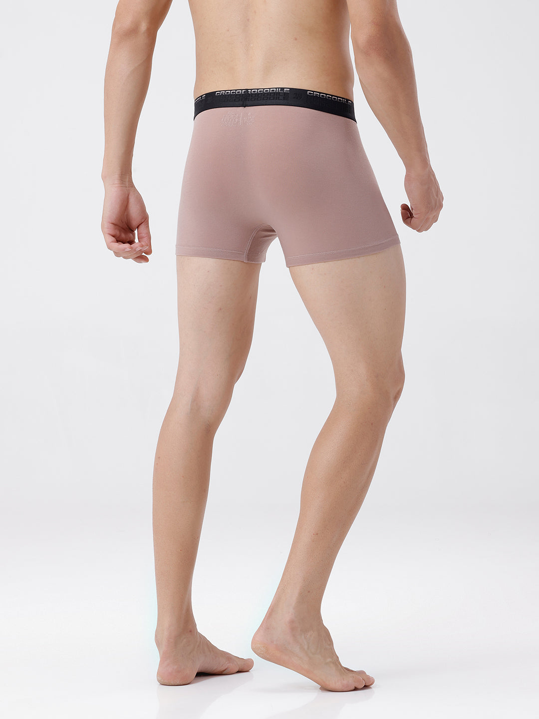 Person wearing a beige boxer brief with black waistband on a white background