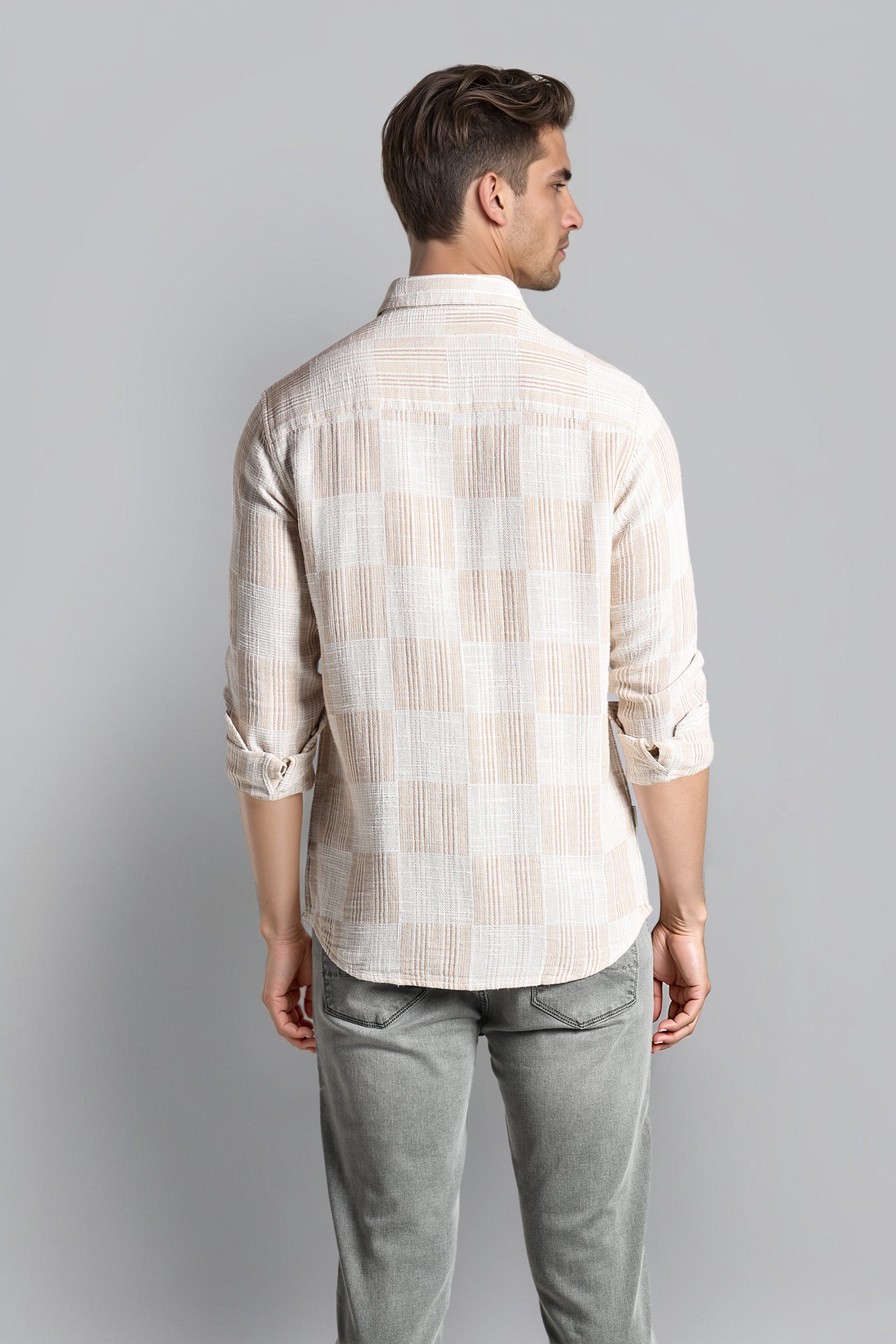 Man wearing a checkered shirt and gray pants against a plain background