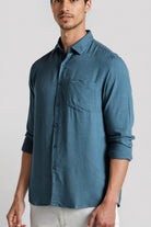 Man wearing a blue button-up shirt on a white background