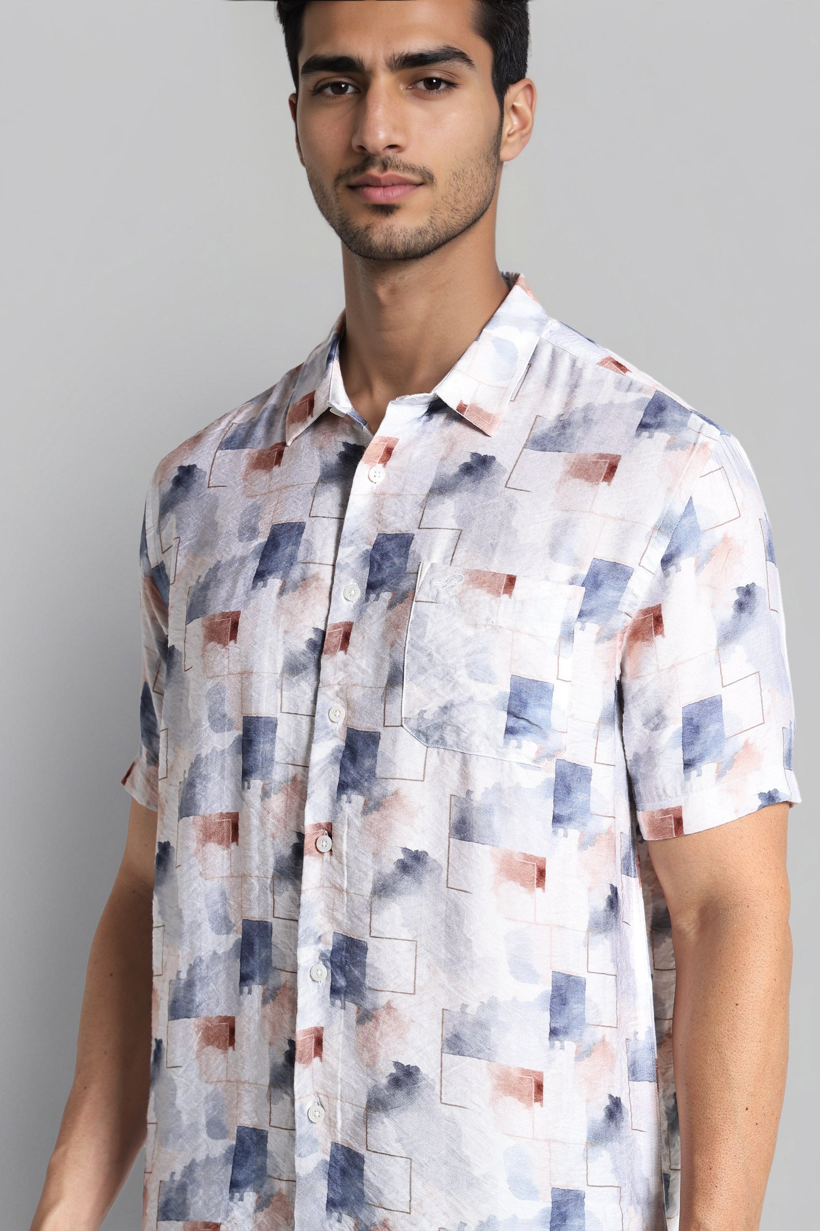 Man wearing a short-sleeve shirt with a geometric pattern on a gray background