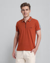 Man wearing a brown trendy stretch zipper polo with tape in brown with casual styling on a gray background