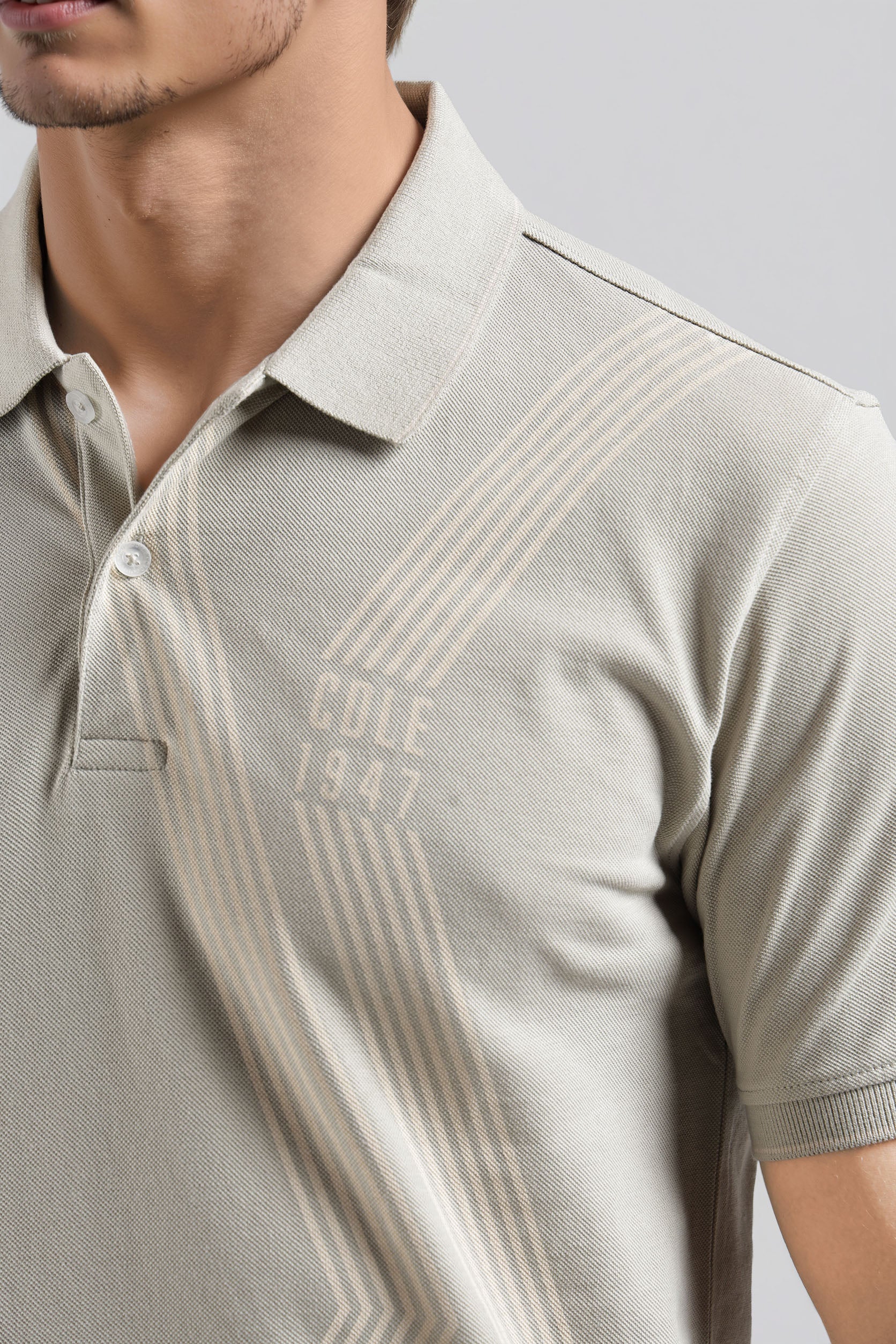 Beige polo shirt with 'Cole 1947' branding on a plain background