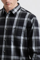 Person wearing a black and gray plaid shirt against a white background