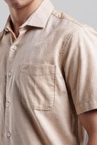 Close-up of a beige short-sleeve shirt with a pocket on a neutral background