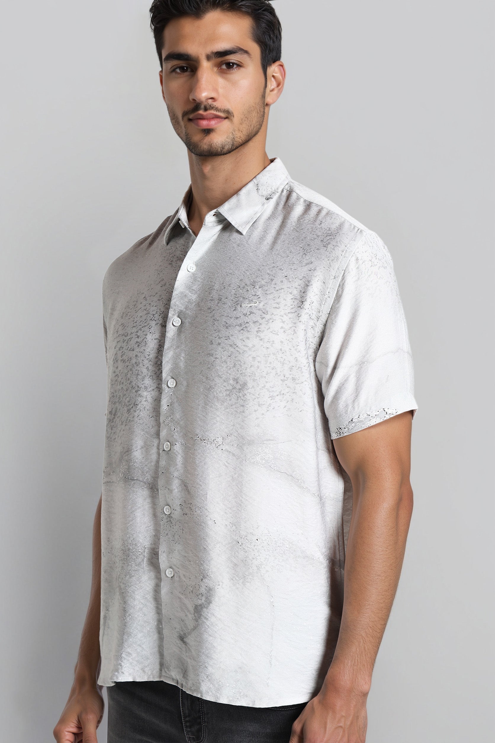 Man wearing a light gray patterned shirt against a plain background