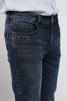 Dark blue jeans worn by a person on a plain background