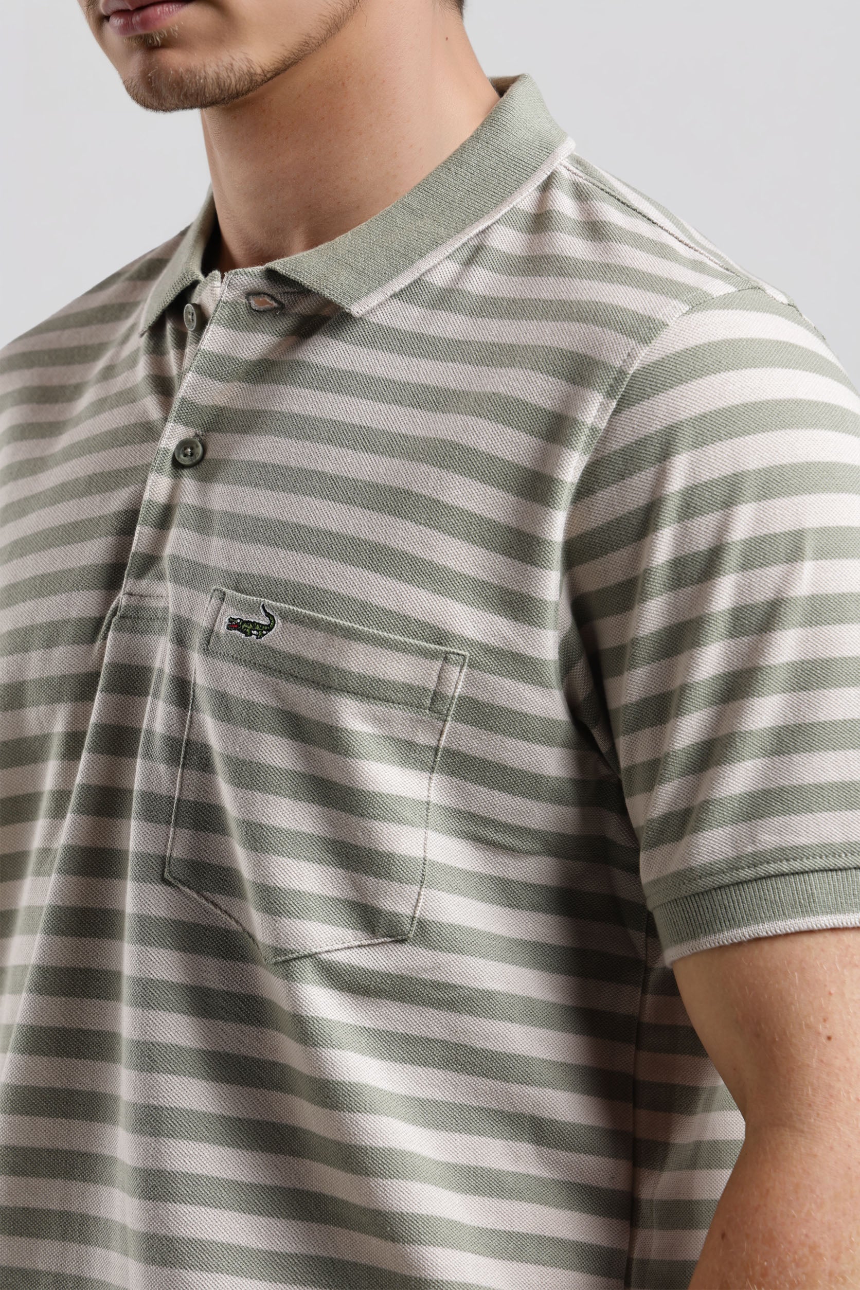 Man wearing a striped polo shirt with a neutral background