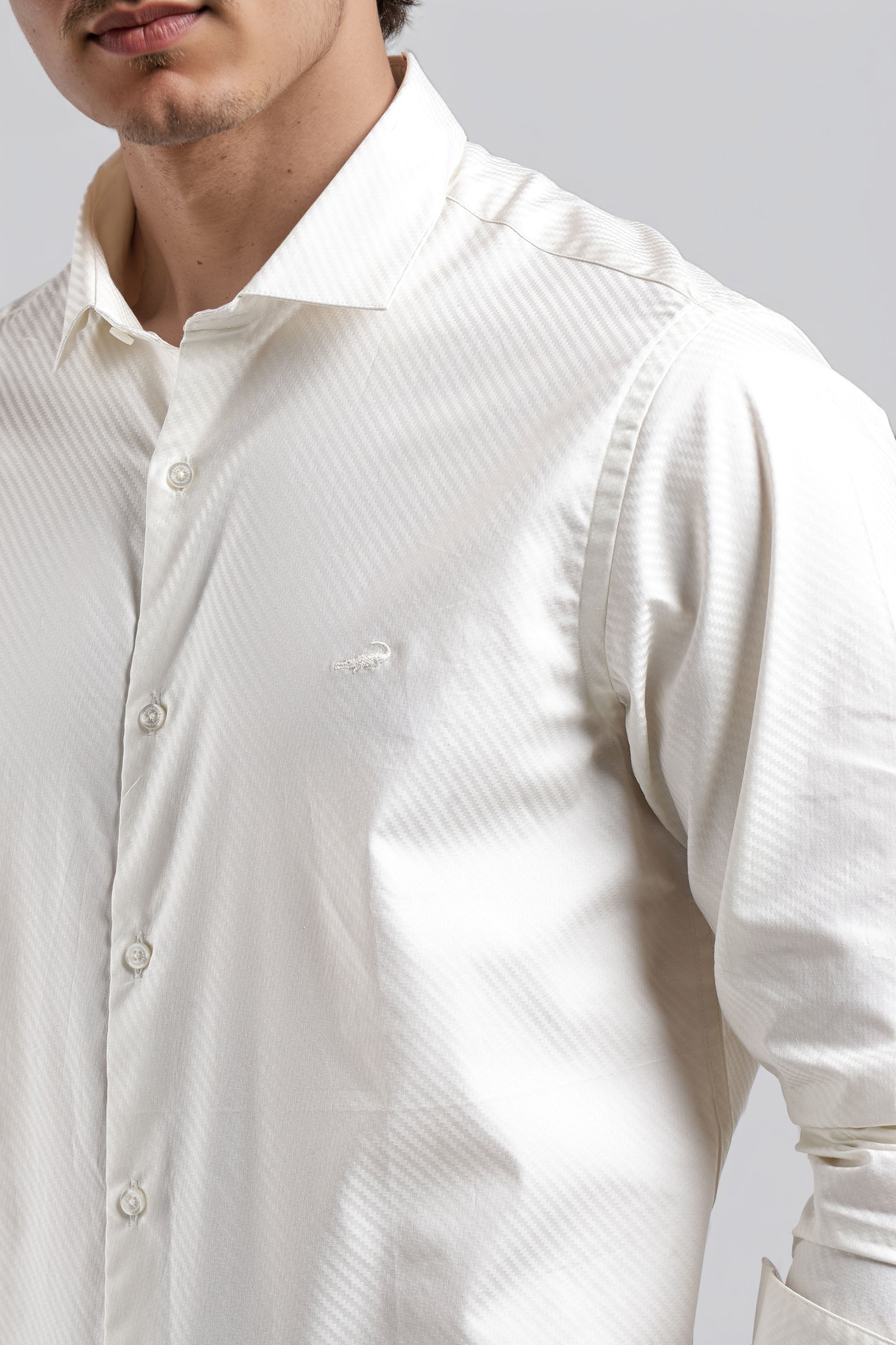 Close-up of a person wearing a white textured shirt on a gray background
