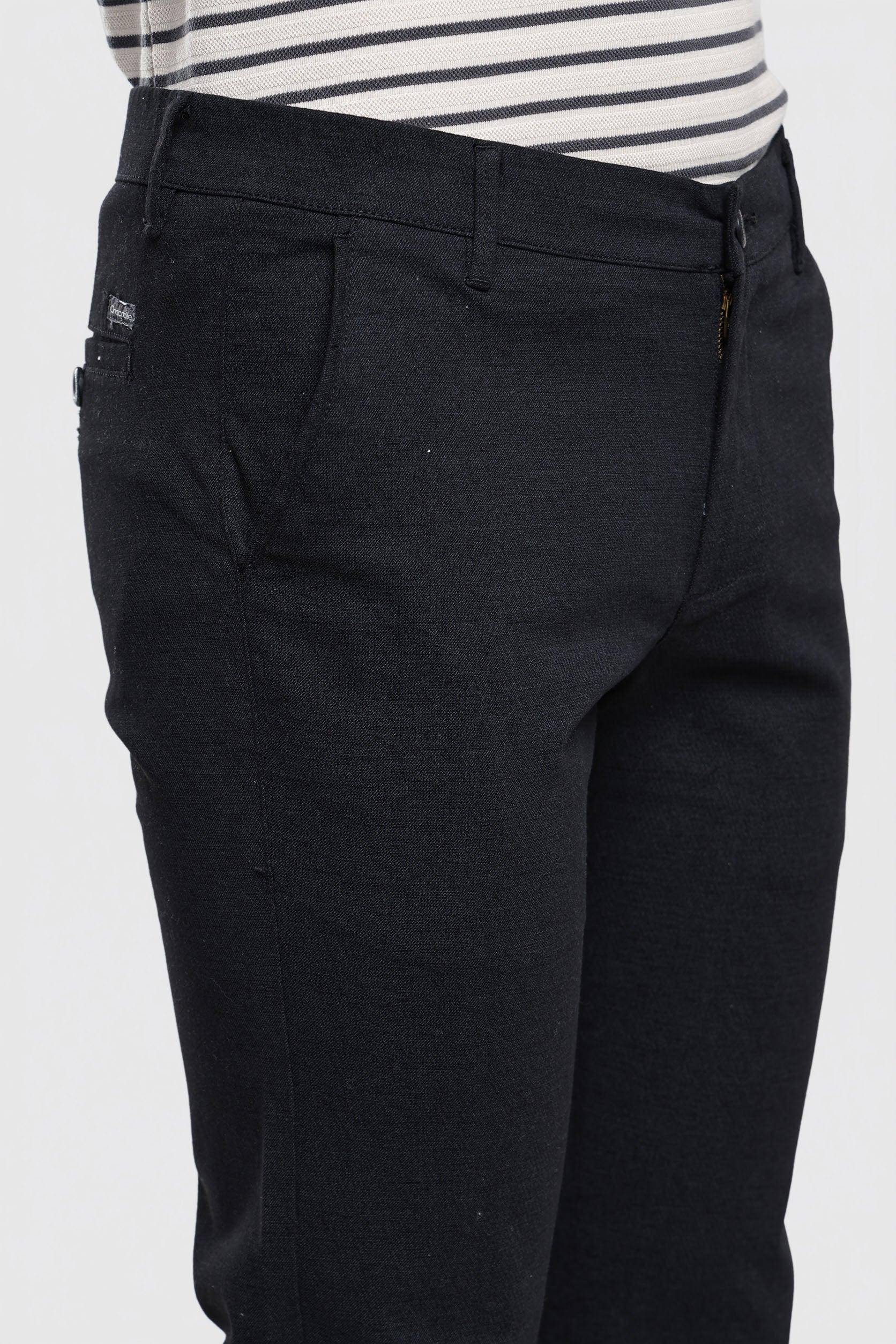 Black pants worn with a striped shirt on a white background