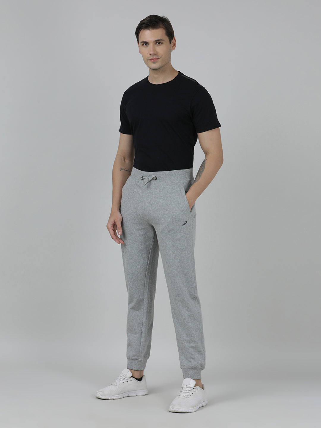 Man wearing a black t-shirt and gray sweatpants on a plain background