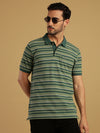 Man wearing a green green striped polo t shirt on a light gray background