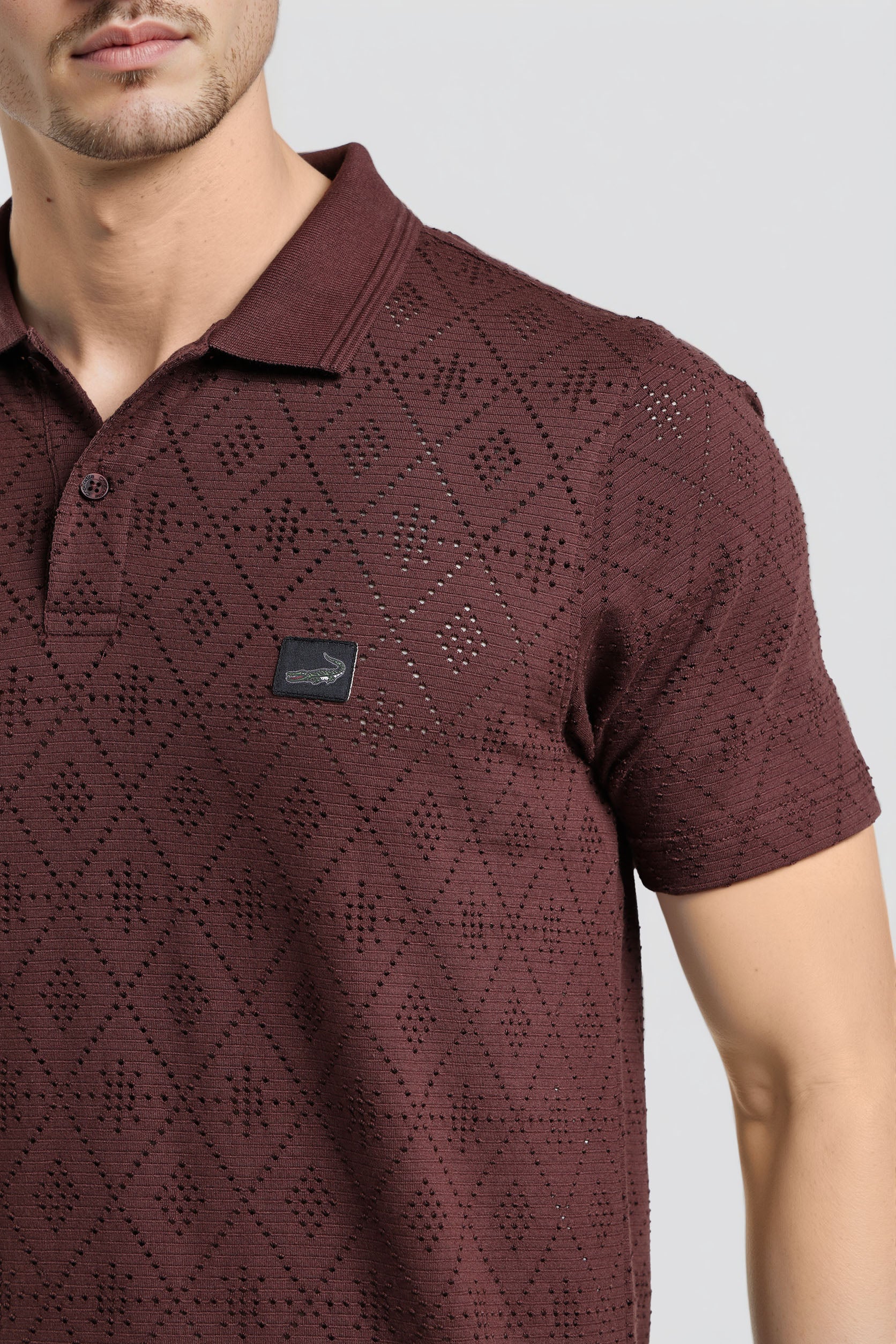 Maroon patterned polo shirt worn by a person on a light gray background