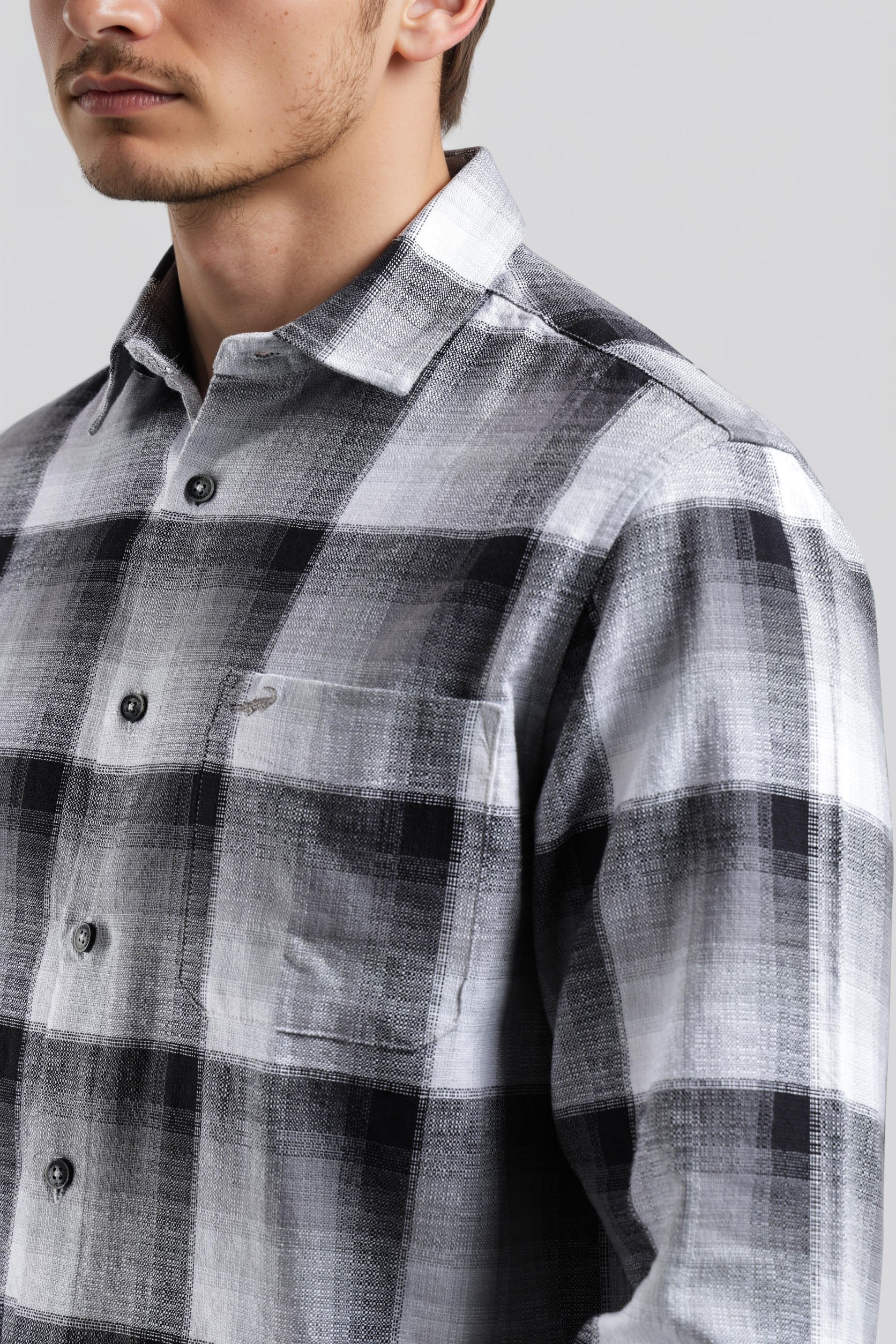 Man wearing a gray and white plaid shirt against a plain background