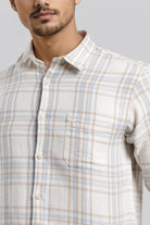 Man wearing a beige and blue plaid shirt against a gray background