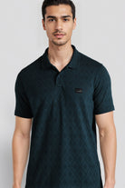 Man wearing a dark green patterned polo shirt on a light gray background