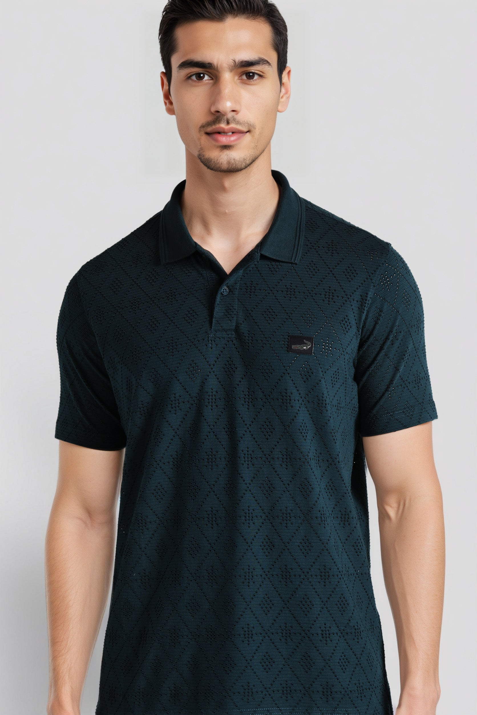 Man wearing a dark green patterned polo shirt on a light gray background