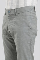 Gray pants worn with a white shirt on a plain background