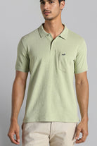 Man wearing a light green polo shirt with a small logo on a gray background