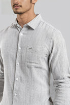 Man wearing a gray striped shirt with a brand logo on a gray background