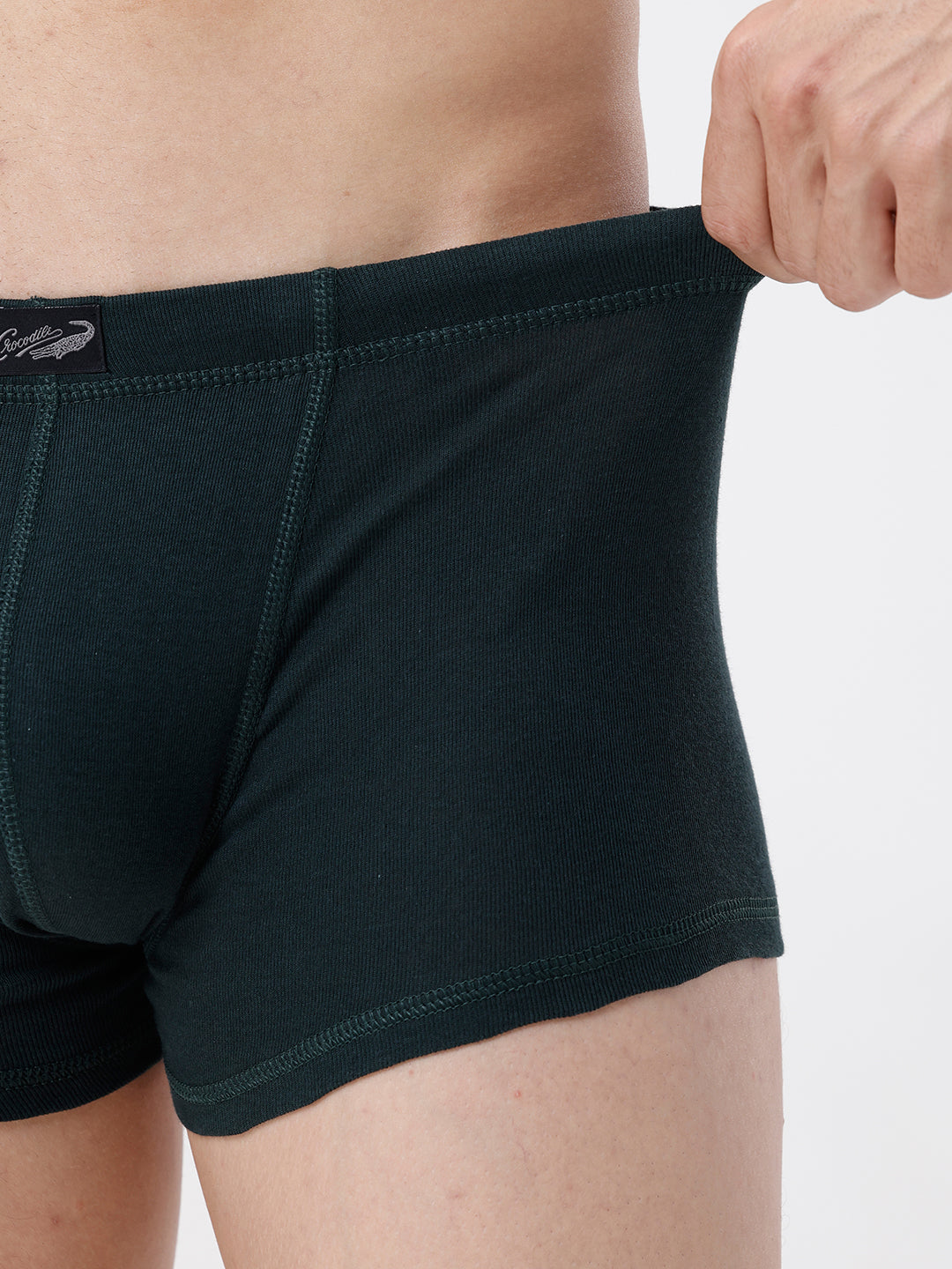 Person wearing dark green boxer briefs with a visible brand logo on a light gray background