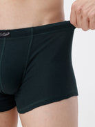 Person wearing dark green boxer briefs with a visible brand logo on a light gray background