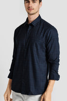 Man wearing a dark blue checkered shirt on a light gray background