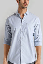 Man wearing a light blue button-up shirt against a plain background