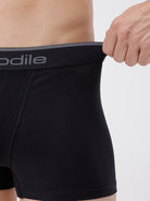 Person wearing black underwear with a visible brand logo on a plain background