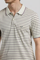 Man wearing a striped polo shirt with a brand logo on a light gray background