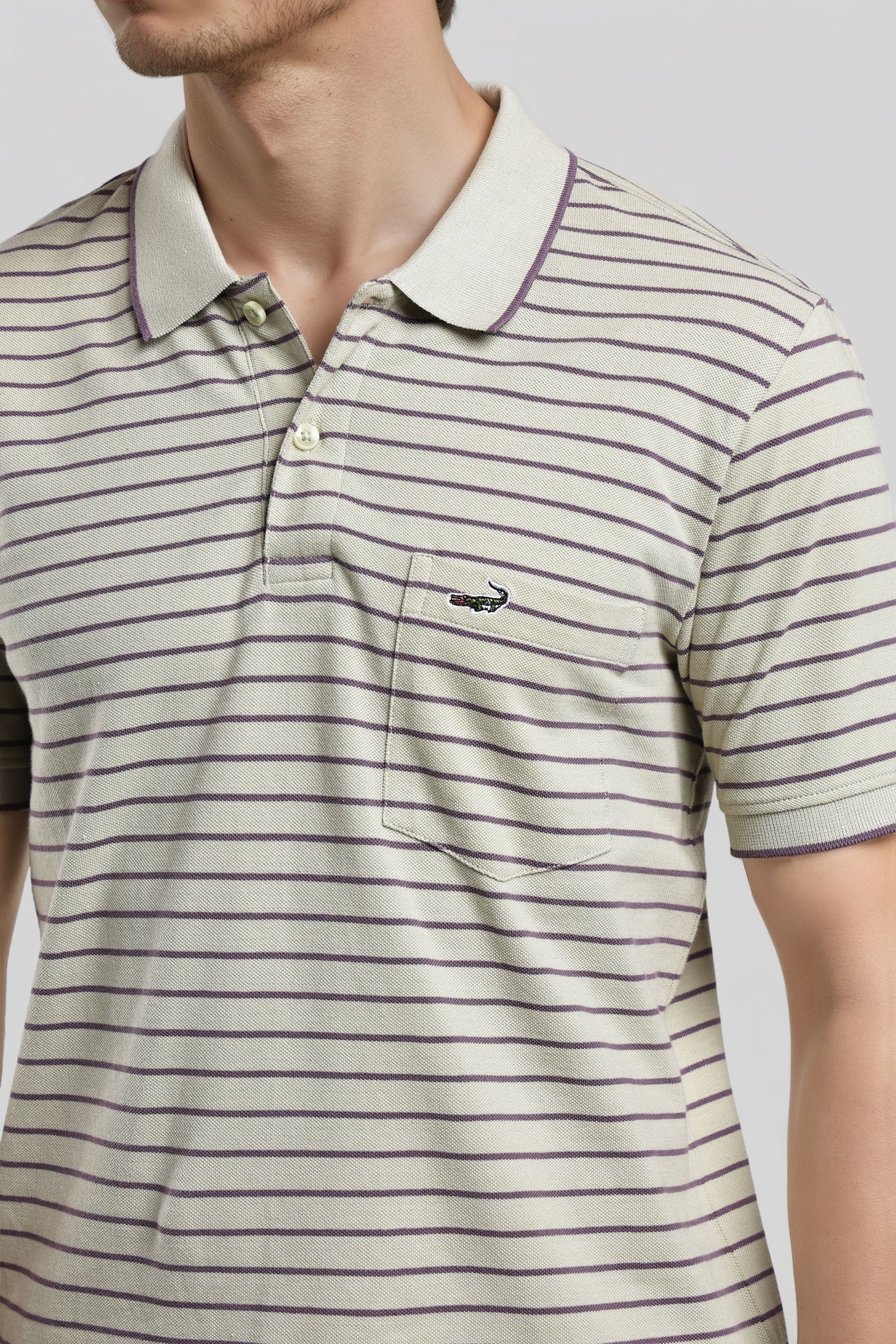 Man wearing a striped polo shirt with a brand logo on a light gray background