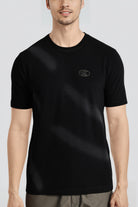 Person wearing a black t-shirt with a logo on a light gray background