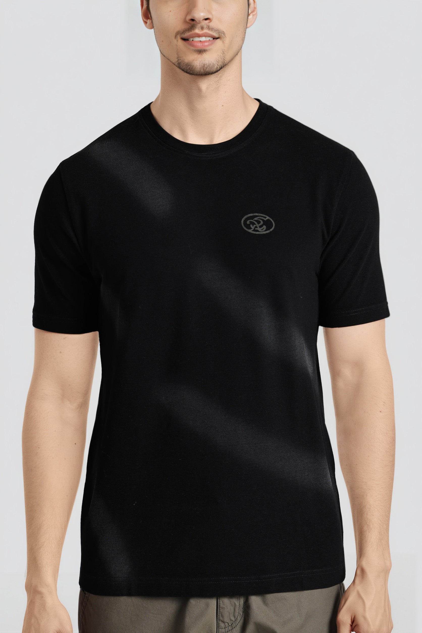 Person wearing a black t-shirt with a logo on a light gray background