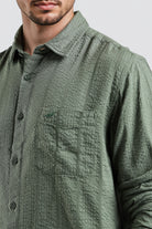 Green textured shirt worn by a person on a light gray background